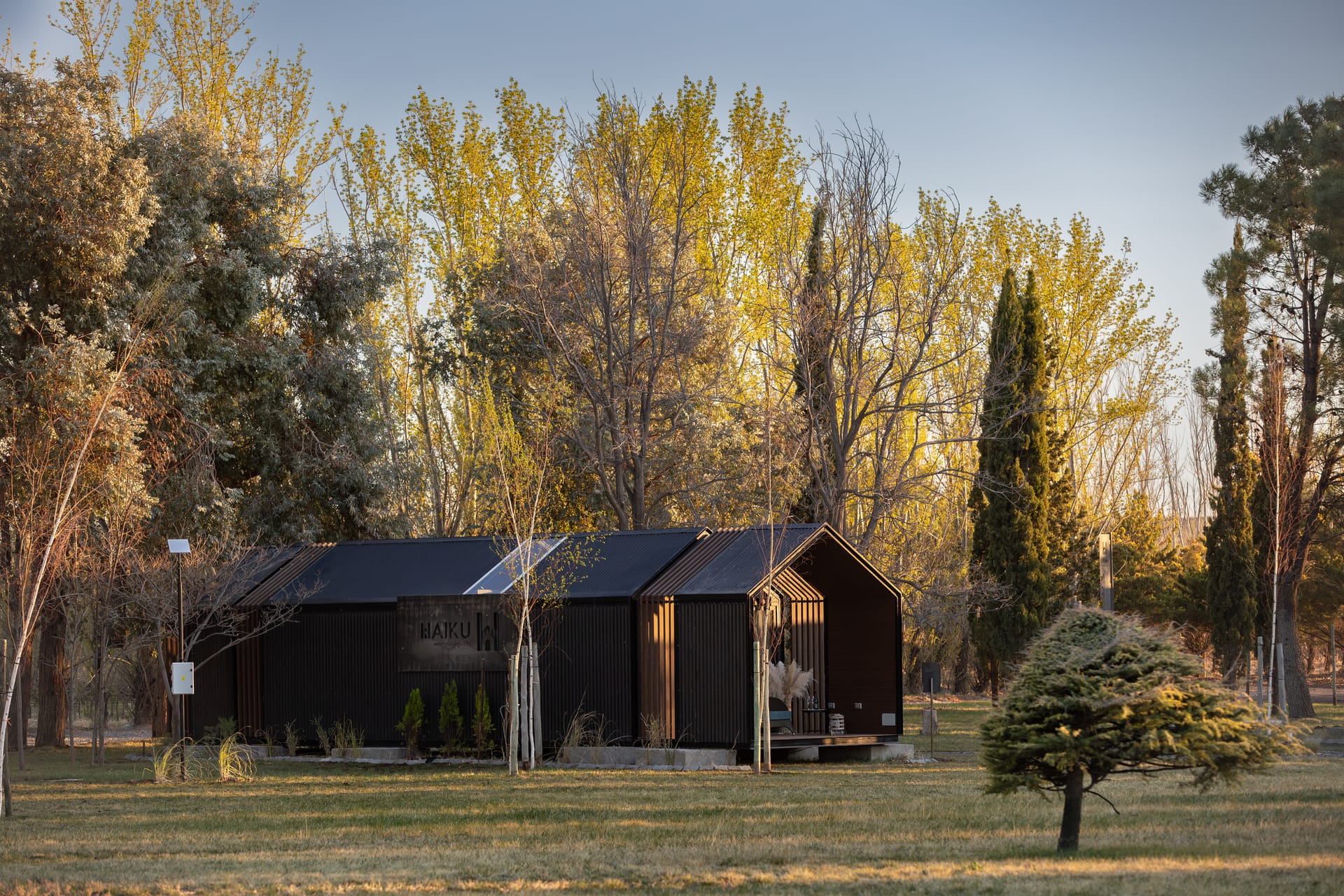 Módulo Haiku A: cabaña de techo a dos aguas con revestimiento de madera y deck, al atardecer en la Patagonia